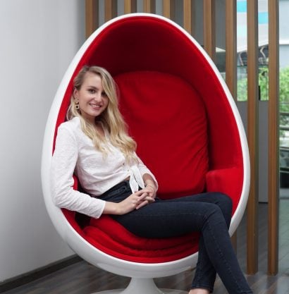A woman smiling and relaxing in a red chair after a LED teeth whitening session at The Smile Bar Philippines.