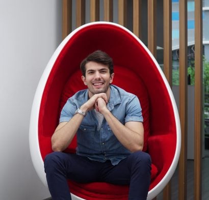 A man smiling after LED teeth whitening at The Smile Bar Philippines, sitting in a red egg chair.